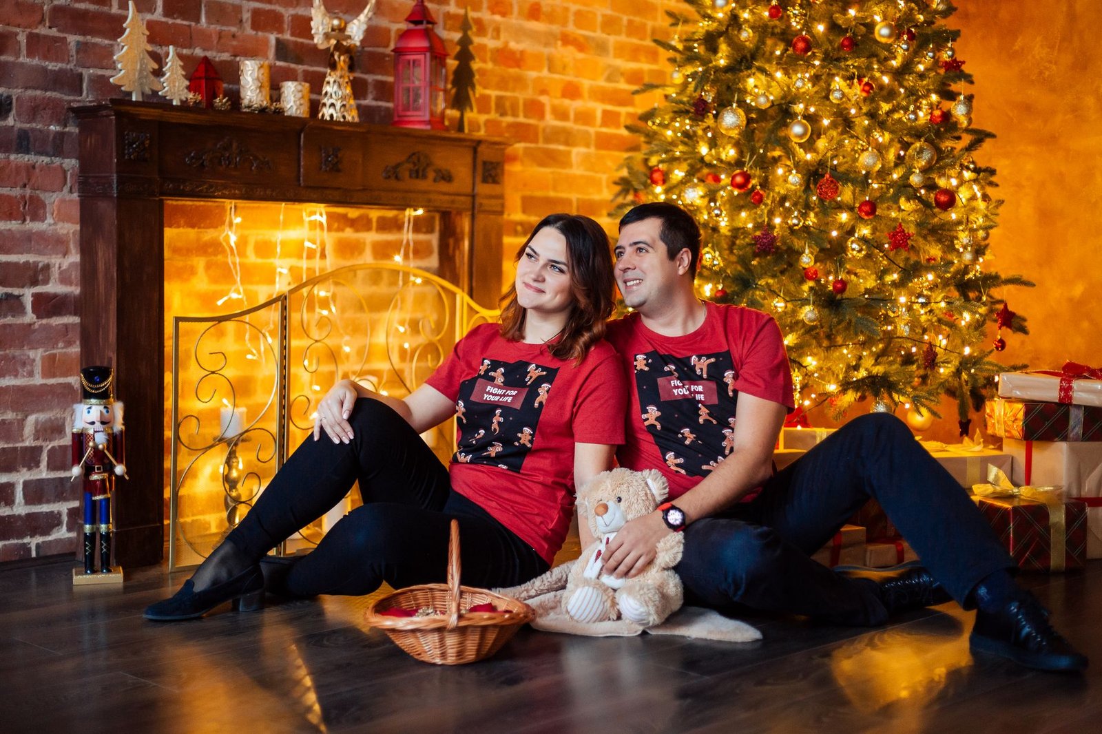 couple with same shirt sitting near christmas tree