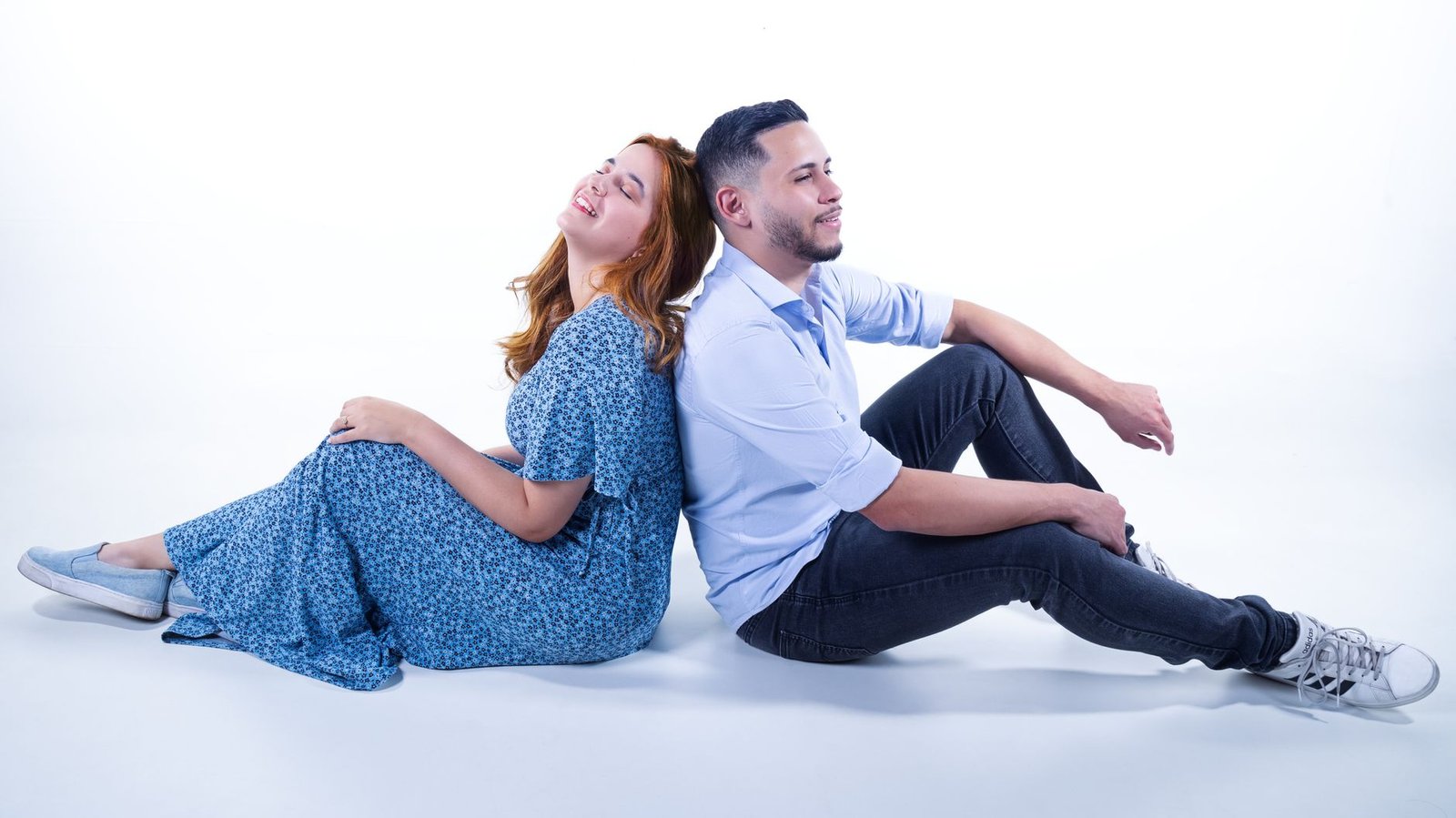 a man and woman sitting on the floor in front of a white background