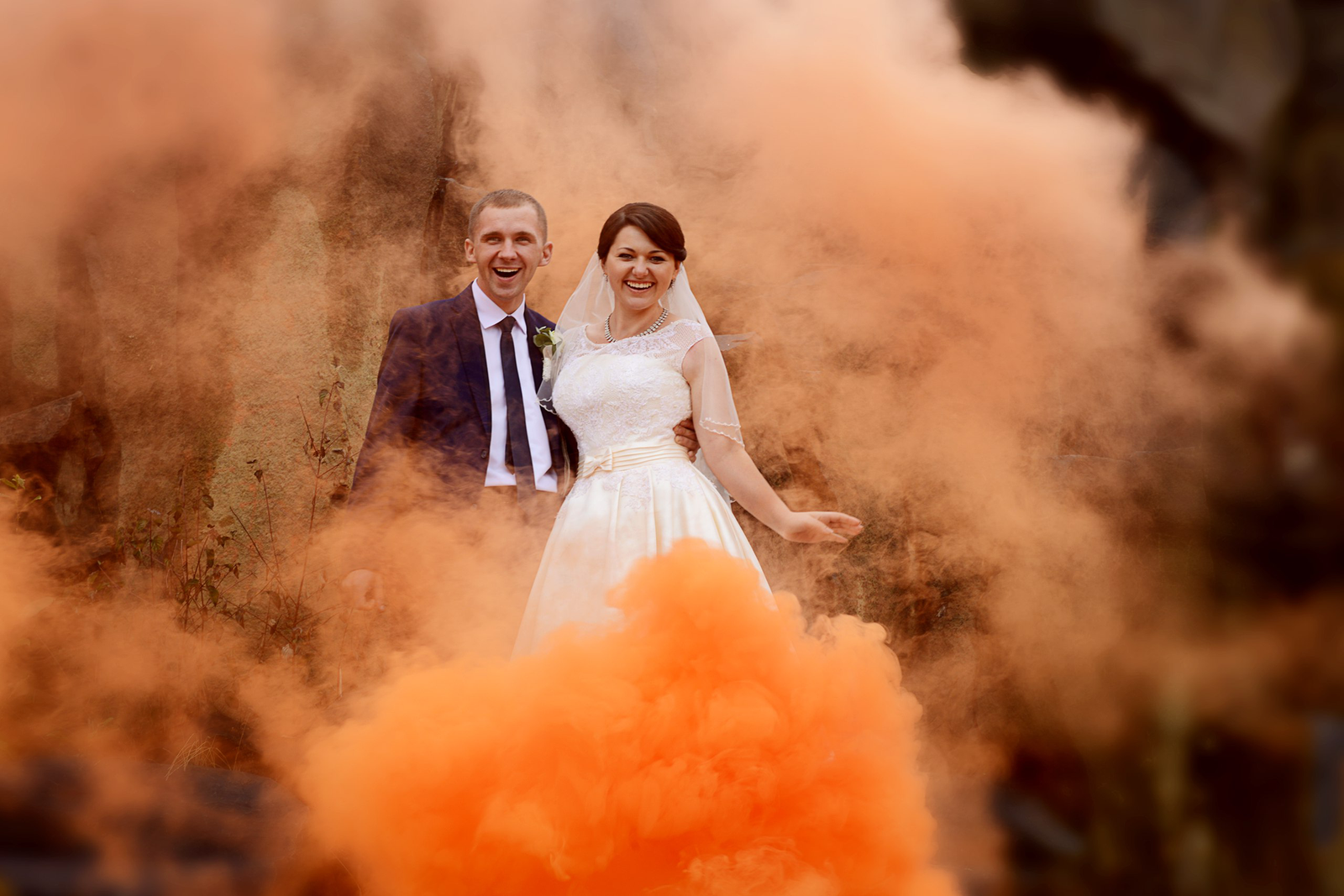 joyful wedding couple in colorful smoke outdoors