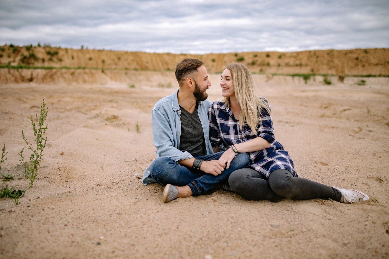 couple sitting on sandy beach and holding hands