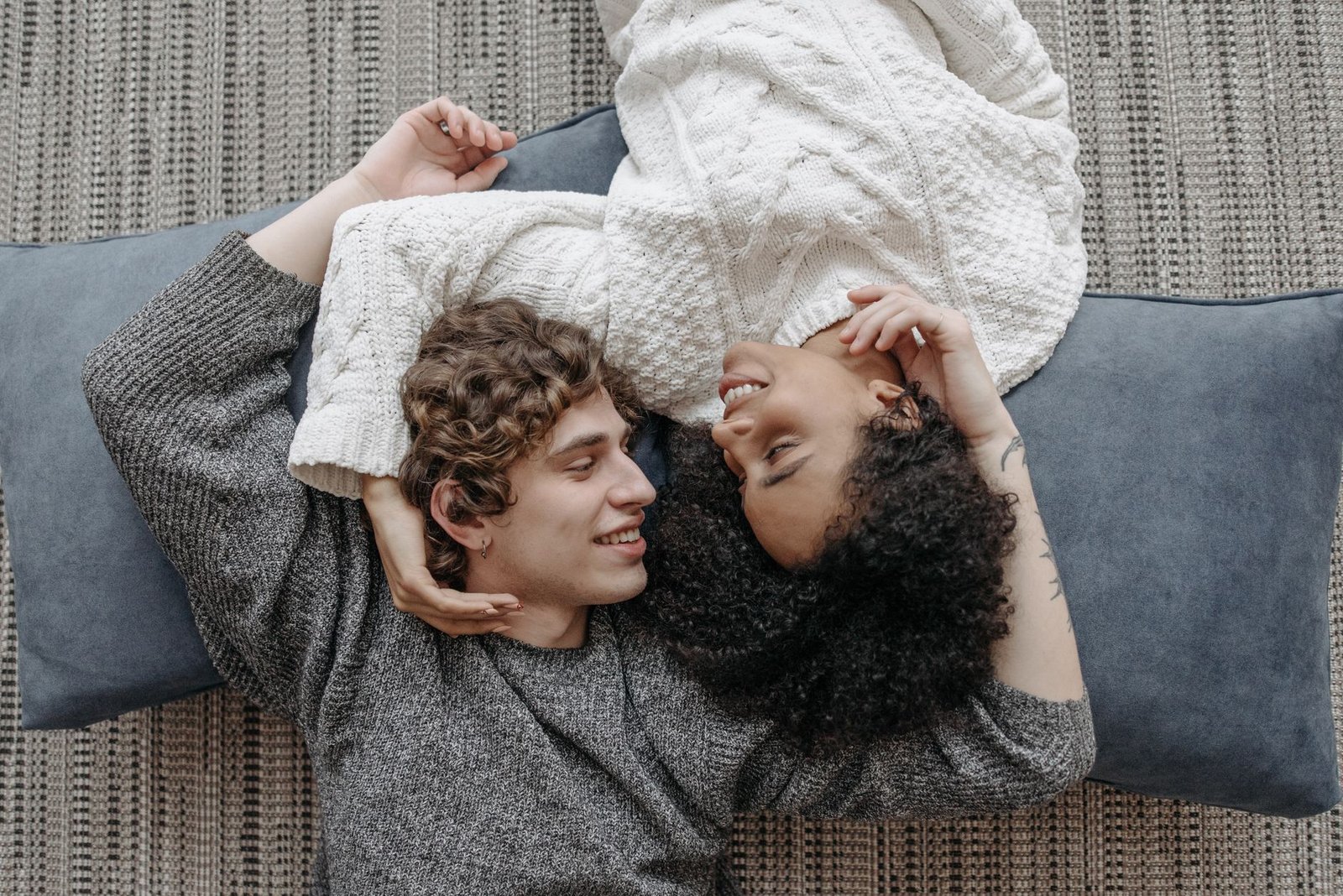 man and woman lying on pillows while looking at each other