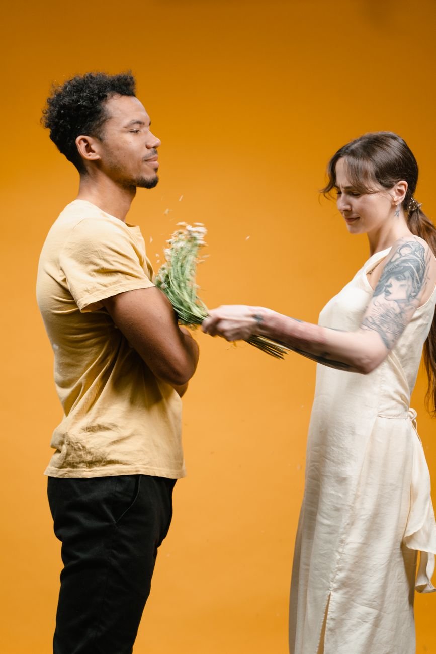 woman in a long dress hitting a man with a bunch of flowers