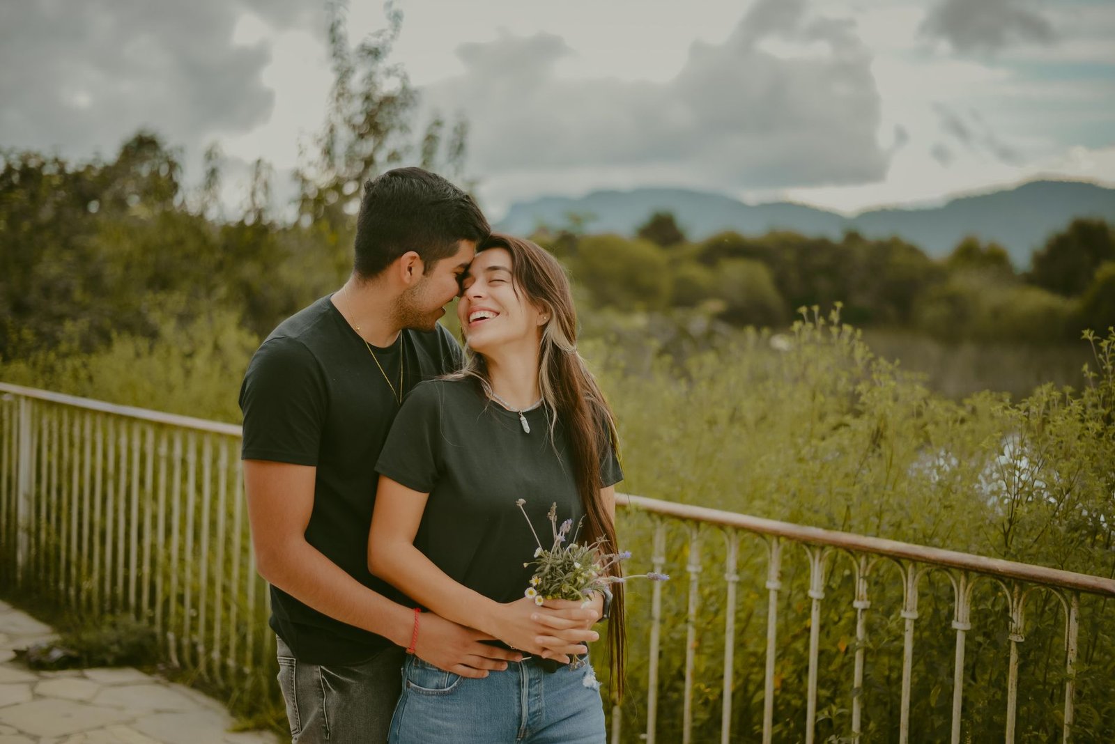 a man hugging a woman holding a bunch of flowers and leaves